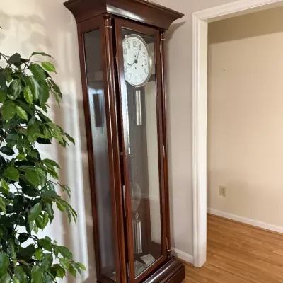 Sale Photo Thumbnail #5: Tall wooden grandfather clock with glass panels, silver-tone weights, and a white dial face.