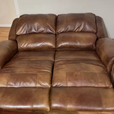 Sale Photo Thumbnail #11: Brown leather dual-reclining loveseat with brass nailhead trim along the rolled arms.