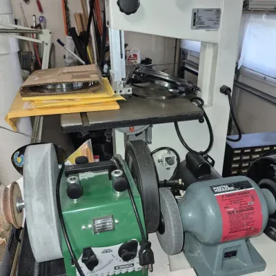 Workshop sharpening station featuring a Tormek wet grinder, a Master Mechanic 8-inch bench grinder, and a Rikon band saw.