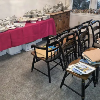 Large collection of fine floral china tableware arranged on a cloth-covered folding table, alongside traditional black painted stenciled...