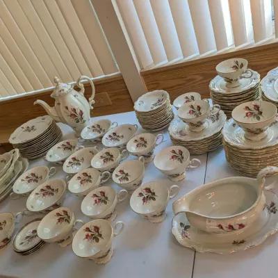 Large vintage porcelain dinnerware set decorated with pink floral rose motifs and gold trim, including a coffee pot, gravy boat, teacups,...