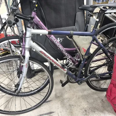 Schwinn silver and purple hybrid bicycle featuring a lightweight aluminum frame and a frame-mounted storage pouch.