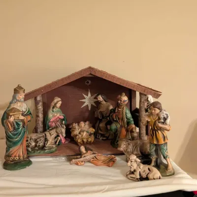Vintage painted nativity set featuring a wooden creche and multiple porcelain or chalkware figurines, including Mary, Joseph, baby Jesus,...