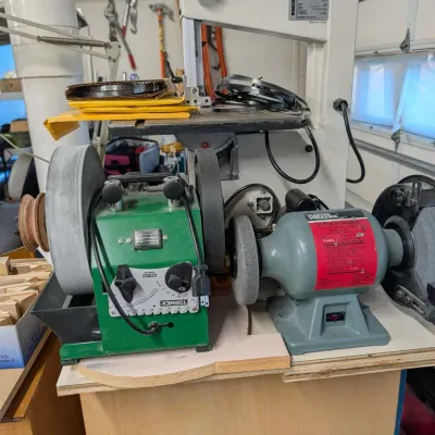 Workshop sharpening and cutting setup featuring a green Tormek water-cooled sharpener, a Master Mechanic bench grinder, and a Rikon...