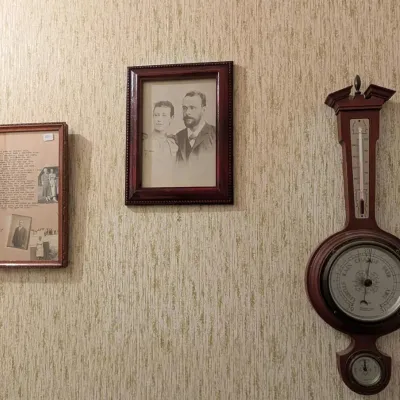 Collection of vintage wall decor including a traditional wood banjo barometer and two framed historic portraits.