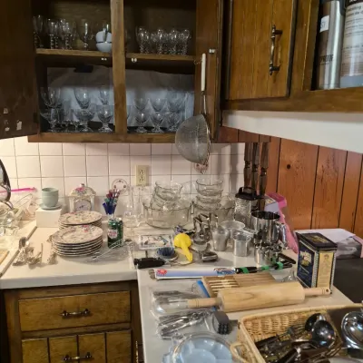 Collection of kitchenware, including crystal stemware in cabinets, stacked china plates, glass bowls, rolling pin, and various kitchen...