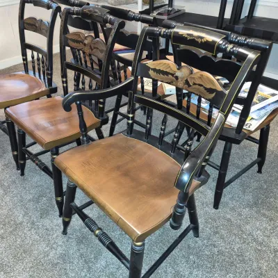 Set of black-painted Hitchcock-style wooden dining chairs featuring hand-painted eagle motifs on the backrests and natural wood seats.