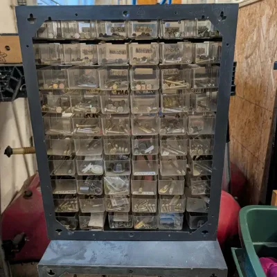 Black plastic multi-drawer small parts organizer filled with assorted hardware including bolts, screws, and fasteners.