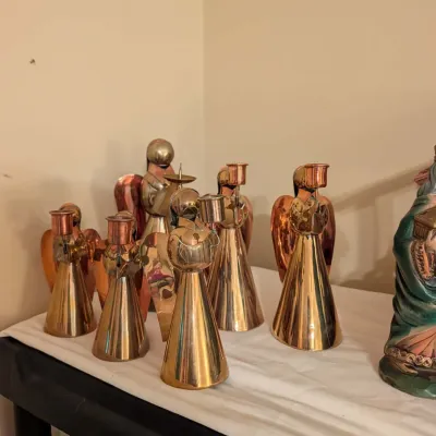 Collection of mid-century brass and copper angel candle holders in varying sizes.