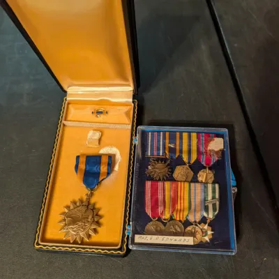 U.S. Air Medal in its original presentation case, displayed alongside a clear plastic case containing a miniature military medal rack...
