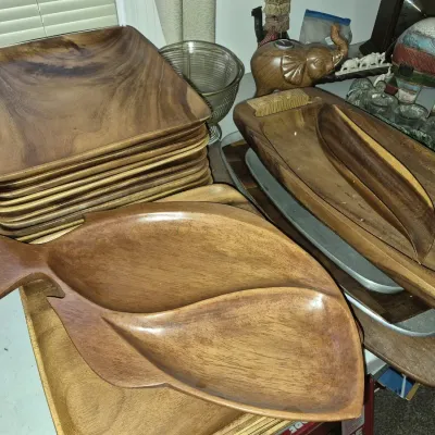 Collection of vintage carved monkey pod wooden serveware, including a fish-shaped divided tray, long baguette bowls, and square plates.