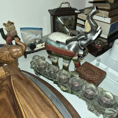 Collection of tabletop decorative items including painted elephant figurines, a leaf-motif votive candle holder, a wooden mantle clock,...