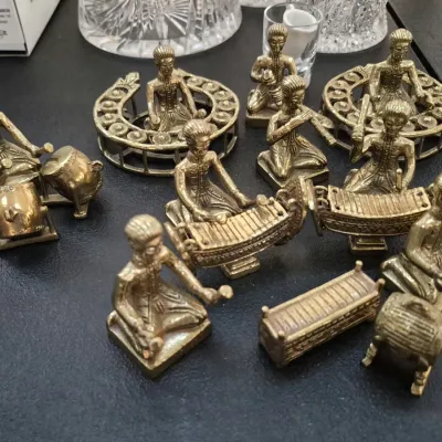 Miniature brass Thai or Balinese orchestra figurine set depicting traditional musicians with various instruments.