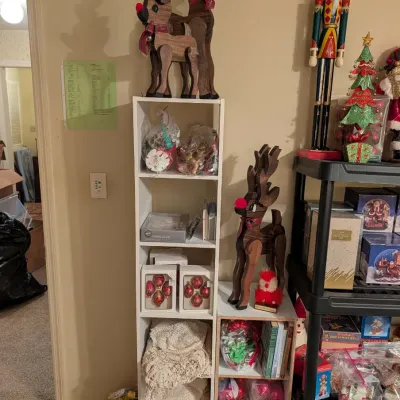 Collection of Christmas decorations including wooden reindeer figures, boxed glass ornaments, a tall nutcracker, and assorted holiday...