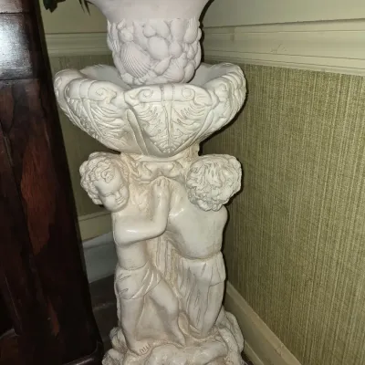 Off-white molded pedestal fountain or planter featuring cherub figures and shell motifs, marked 'MEXICO' at the base.