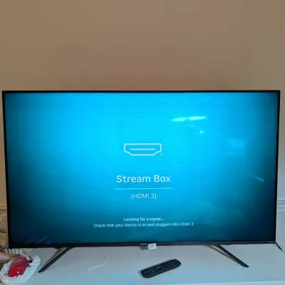 Hisense 55-inch flat-screen smart TV set up on a stand, powered on and displayed with a remote control.
