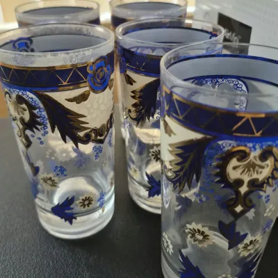 Set of five vintage drinking glasses featuring intricate cobalt blue and gold scrollwork graphics on clear glass.