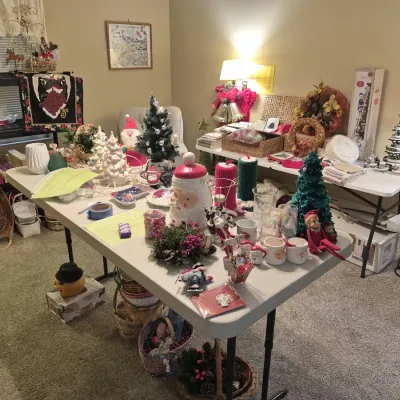 Large assortment of vintage and contemporary Christmas decor displayed on folding tables, including ceramic trees, Santa figurines,...