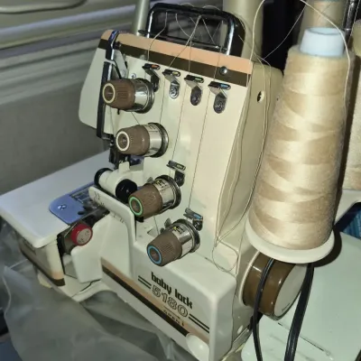 Vintage Baby Lock model 5180 serger sewing machine, fully threaded with spools of beige thread.