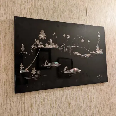 Black lacquer wall panel with mother-of-pearl inlay depicting a Vietnamese coastal scene with palm trees and boats.