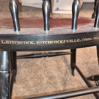 Detail view of a black Hitchcock wooden chair displaying the gold stencil maker's mark reading 'L. HITCHCOCK. HITCHCOCKS-VILLE....