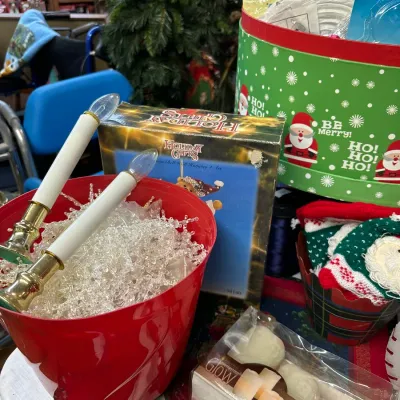 Sale Photo Thumbnail #23: Collection of holiday decorations, including a red bucket filled with clear icicle garland, electric window candles, a boxed set of LED flameless candles, and festive gift boxes.