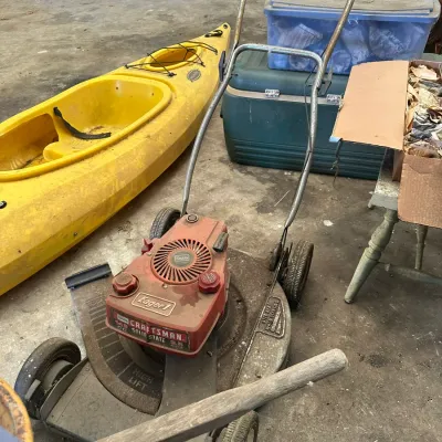 Sale Photo Thumbnail #565: Vintage Sears Craftsman Eager-1 push lawn mower with a red motor casing, set in a garage alongside a bright yellow kayak.