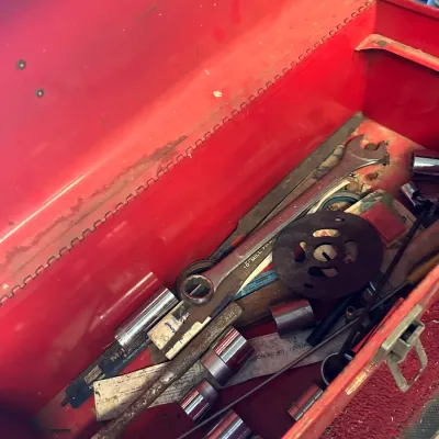 Sale Photo Thumbnail #487: Red metal toolbox filled with various hand tools, including combination wrenches, sockets, files, and small hardware parts.