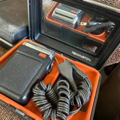 Sale Photo Thumbnail #619: Vintage Remington electric shaver set in its original hard shell case with a built-in mirror and coiled power cord.