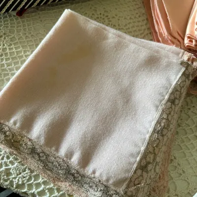 Sale Photo Thumbnail #596: Folded light pink vintage cloth napkins or handkerchiefs featuring lace borders, showing light surface staining.