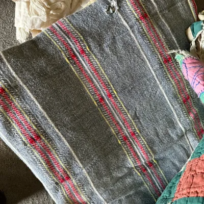 Sale Photo Thumbnail #354: Vintage woven wool blanket in grey with red and yellow striped accents, showing minor wear and a small tear.
