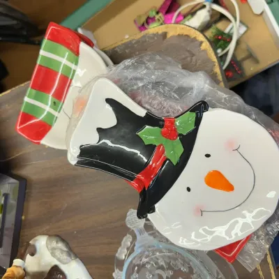 Sale Photo Thumbnail #316: Festive snowman-shaped ceramic spoon rest accompanied by other holiday tableware and decor items.