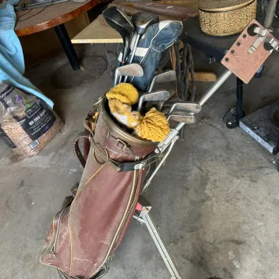 Sale Photo Thumbnail #710: Vintage brown leather golf bag filled with assorted golf clubs, mounted on a folding pull cart.