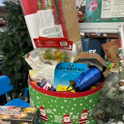 Sale Photo Thumbnail #22: Festive round green Santa-patterned hatbox filled with holiday gift wrapping supplies, including tissue paper, ribbon, a gift wrap kit, and decorative accents.