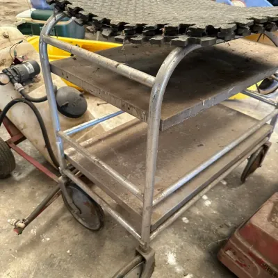 Sale Photo Thumbnail #541: Heavy-duty aluminum multi-shelf utility cart with large caster wheels, showing wear and dust from workshop use.