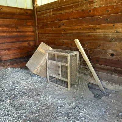 Sale Photo Thumbnail #267: Handmade wooden animal hutch or cage with wire mesh, accompanied by a wooden box and wire tomato cage inside a shed.