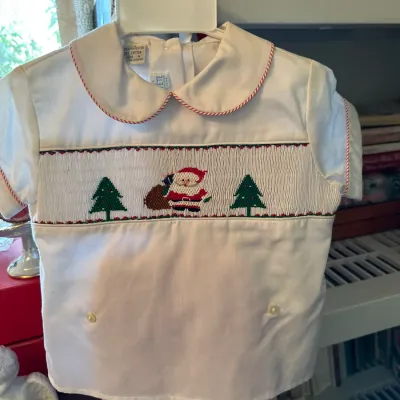 Sale Photo Thumbnail #682: Vintage children's Christmas smocked shirt featuring embroidered Santa and Christmas trees with red piping detail.