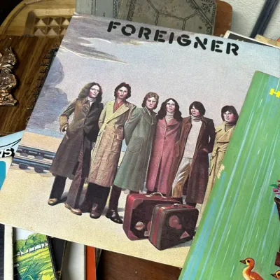 Sale Photo Thumbnail #127: Vintage Foreigner self-titled debut vinyl LP album cover, released in 1977, displayed among a collection of vintage books.