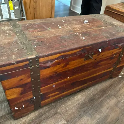 Sale Photo Thumbnail #349: Vintage solid cedar trunk featuring metal corner straps, studded hardware details, and a key lock.