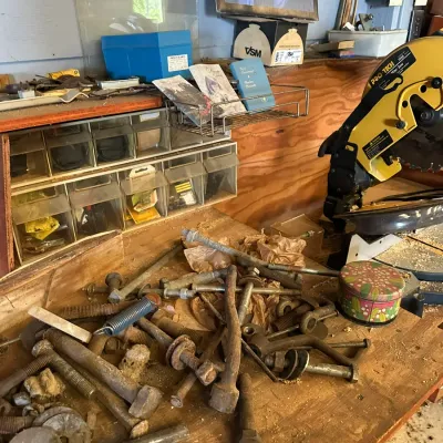 Sale Photo Thumbnail #509: Workshop bench littered with various vintage bolts, nuts, hardware, and a Pro-Tech miter saw in the background.