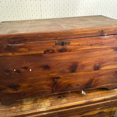 Sale Photo Thumbnail #350: Vintage solid wood cedar chest featuring a natural knotty grain finish and a decorative brass keyhole plate, showing age-appropriate surface wear.