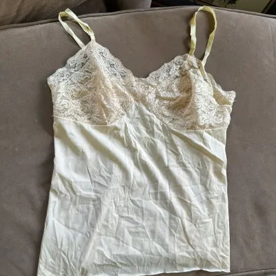 Sale Photo Thumbnail #622: Vintage pale yellow lace-trimmed camisole top featuring thin shoulder straps and delicate floral lace detailing at the bodice.