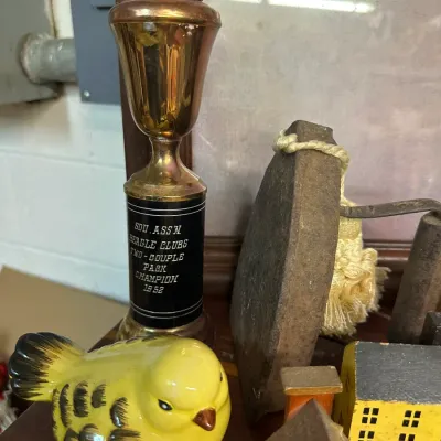 Sale Photo Thumbnail #55: Vintage 1962 Southern Association Beagle Clubs trophy standing alongside a ceramic yellow bird figurine and antique cast iron flatiron.