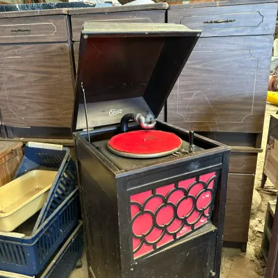 Sale Photo Thumbnail #517: Antique Edison floor-model phonograph featuring a dark wooden cabinet, red fabric speaker grill with fretwork, and a lift-top lid.