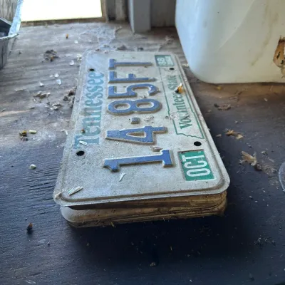 Sale Photo Thumbnail #488: Stack of vintage Tennessee Volunteer State license plates featuring blue embossed lettering with an October expiration tag.