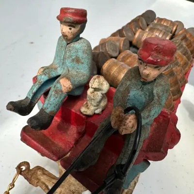 Sale Photo Thumbnail #174: Antique painted cast iron horse-drawn beer wagon featuring driver and passenger figures, small dog detail, and wooden barrel cargo.
