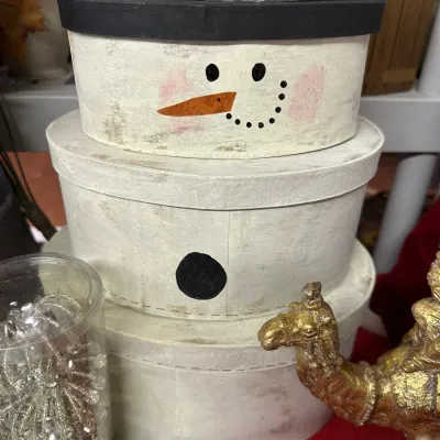 Sale Photo Thumbnail #19: Set of three rustic stacked snowman nesting storage boxes made of painted cardboard, featuring distressed cream finish and painted facial details.