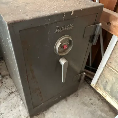 Sale Photo Thumbnail #720: Vintage Diebold steel safe with combination lock dial and heavy-duty handle, showing surface dust and minor rust.