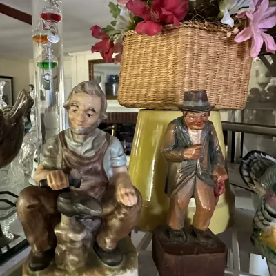 Sale Photo Thumbnail #242: Two vintage character figurines displayed alongside a woven basket with faux flowers and a glass Galileo thermometer.