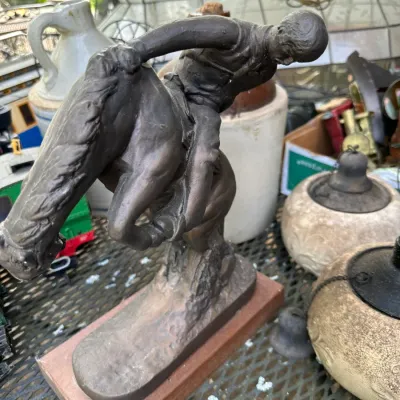 Sale Photo Thumbnail #169: Bronze-finished sculpture of a cowboy riding a bucking bronco mounted on a wooden base.